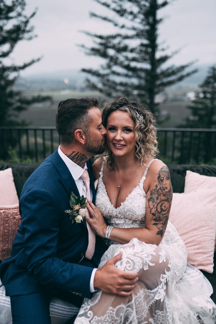 Groom kisses bride on the cheek by The MacLeans Vancouver