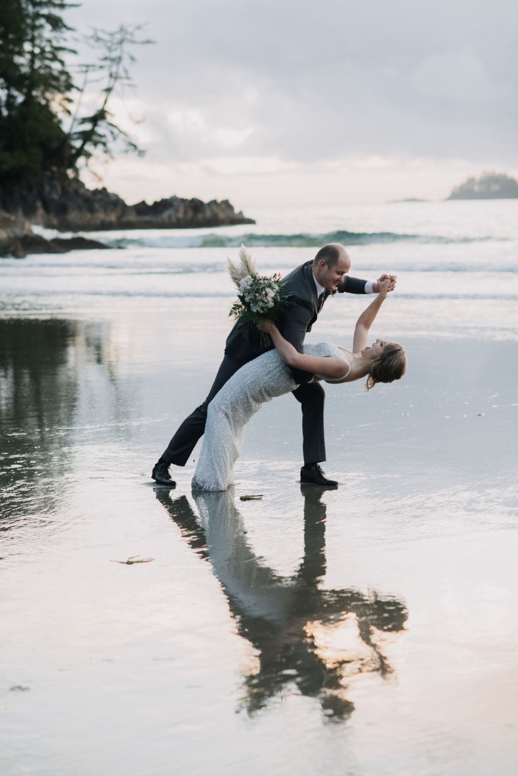 Groom bends his bride backwards on Tofino Beach by Bracey Photography