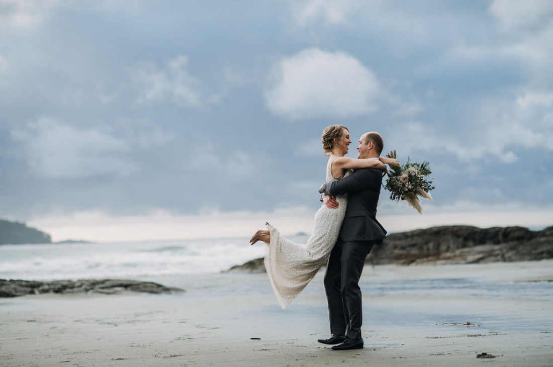 Groom picks up his new wife on the Tofino Beach Vancouver Island