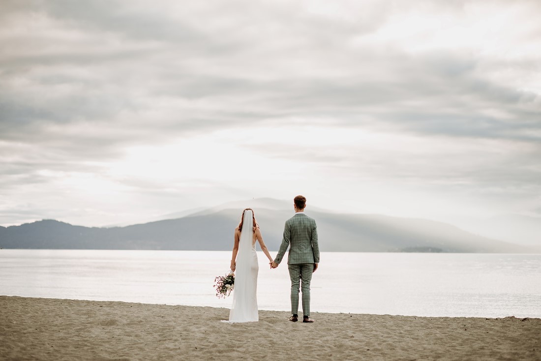 Newlyweds look out at Vancouver mountains with ocean in front of them