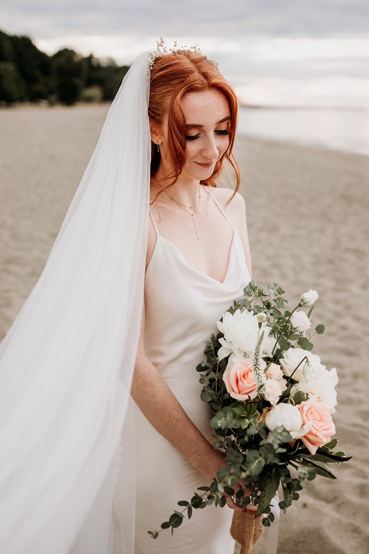 Bride wearing Park and Fifth wedding gown and holding blush and white flower bouquet