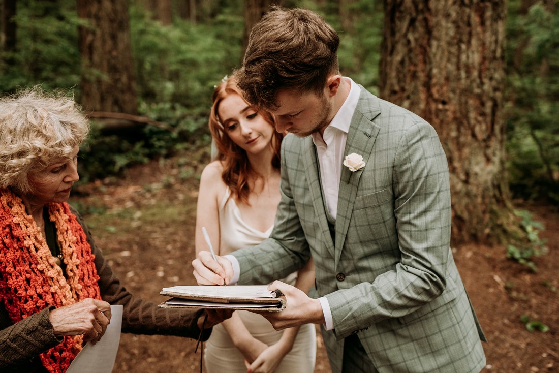 Newlyweds sign register papers in the Vancouver forest