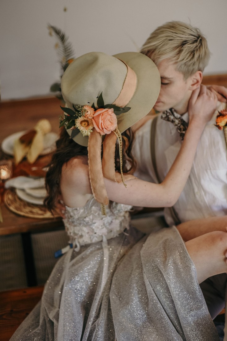 Deep Cove Winery Wedding Dayla Weiss Photo Bride wears bridal hat as she sit across grooms lap