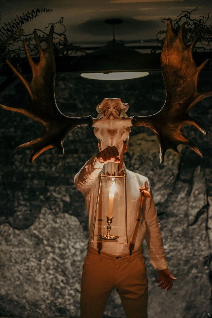 Deep Cove Winery Wedding Dayla Weiss Photo Groom wearing scull with antlers holding a lantern