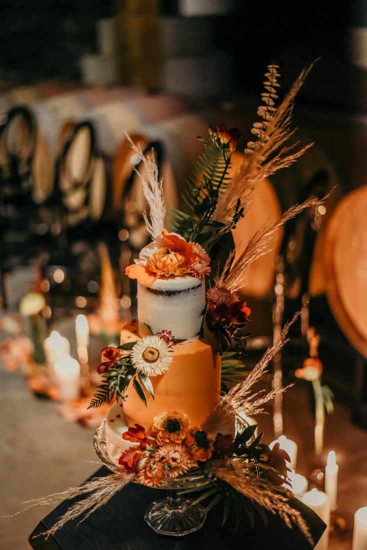 Deep Cove Winery Wedding Dayla Weiss Photo Close - up of boho inspired wedding cake with florals and grasses