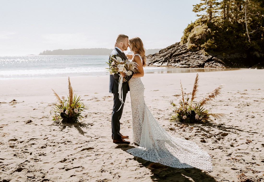 Beach Wed in Tofino couple stand between floral arrangements Crab Appl;e Floral