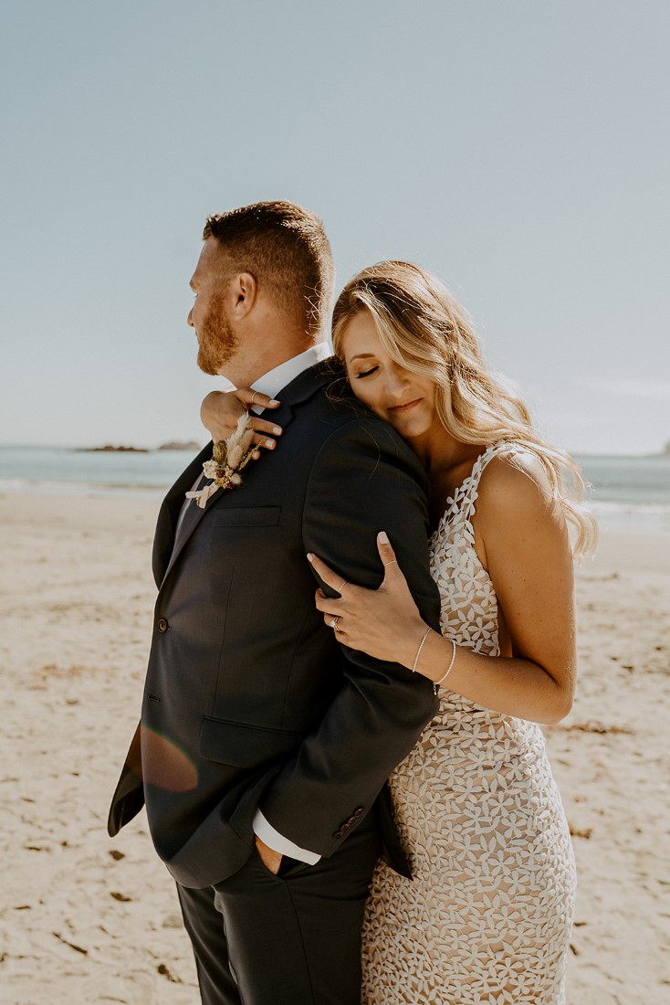Bride leans her head against grooms shoulder on Tofino beach