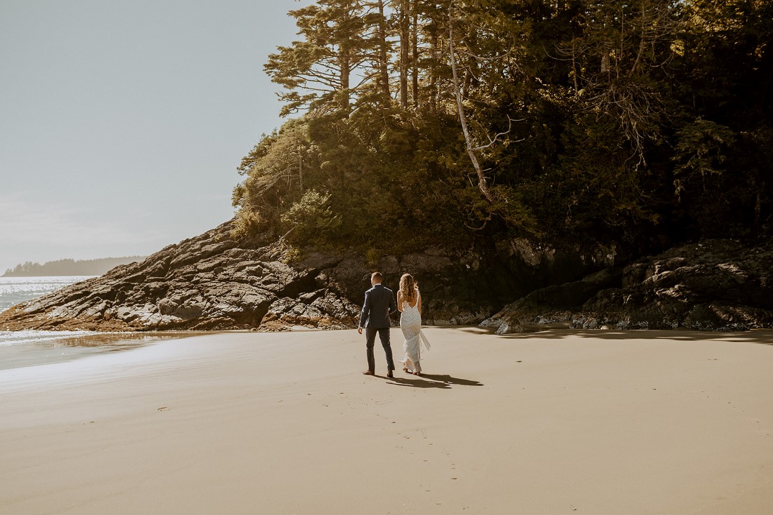 Newlyweds in Tofino walk along ocean edge