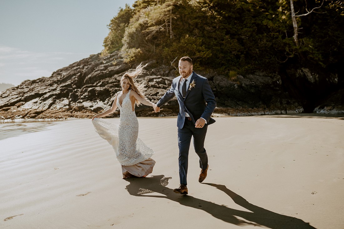 Newlyweds holding hands and running along Tofino beach