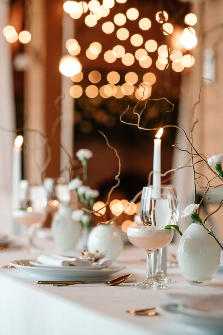 White taper candles on white linens at wedding reception table by Bezaire Events