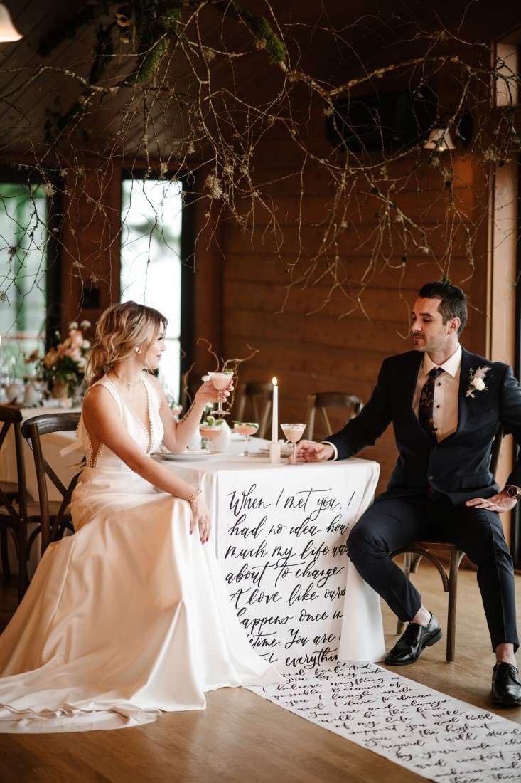 Bride and Groom sit at reception table with calligraphy linen at Dolphin's Resort