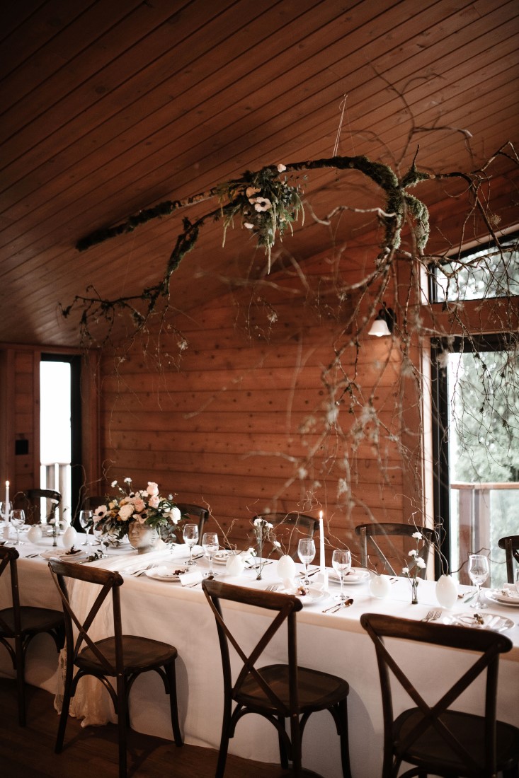 Twigs and flowers hung above wedding reception table by Bezaire Events