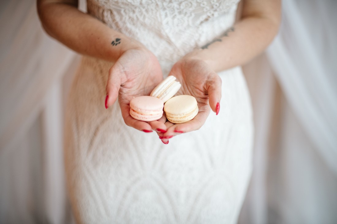 Bride holds blush pink macarons in her hand by OMG Macarons