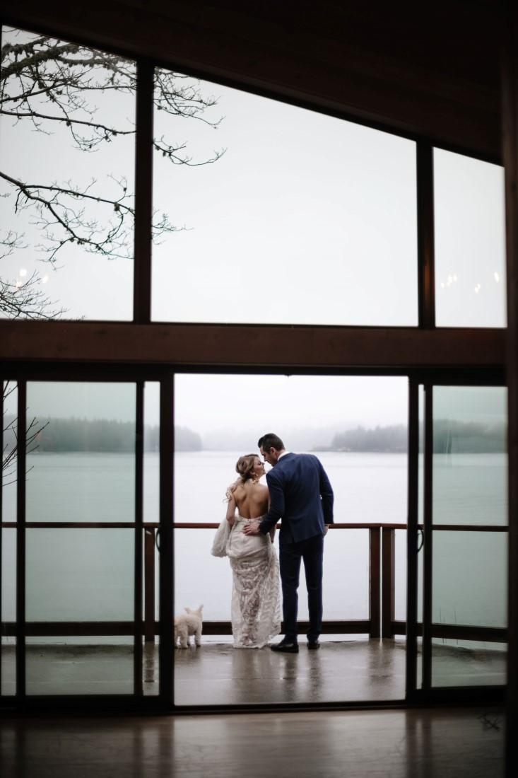 Newlyweds look at ocean through wall of windows at Dolphin's Resort by Erin Wallis Photography