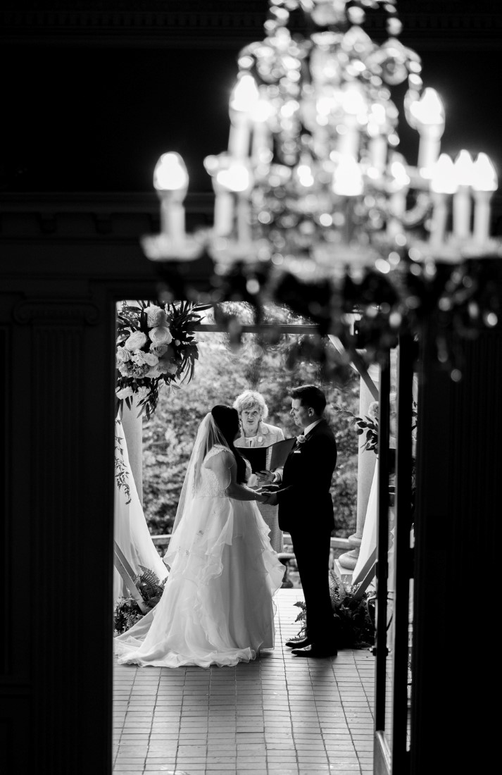 Newlyweds stand in the door framed by chandelier at Hycroft Manor Vancouver by Justin Kho Photography