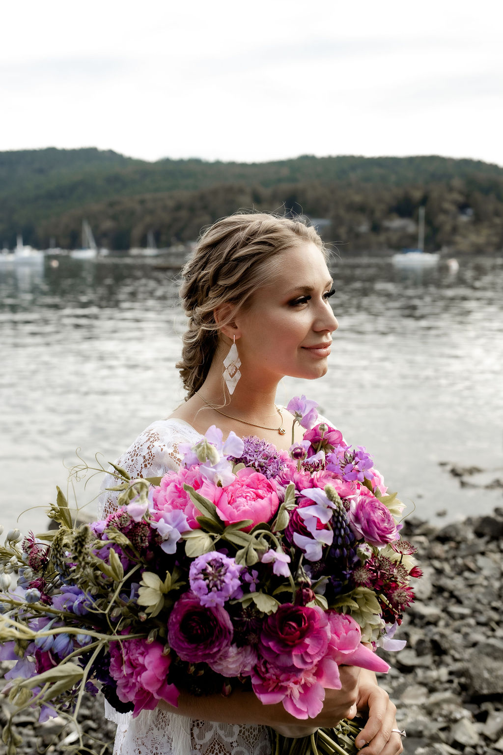 Bride holds pink and purple bouquet beside ocean edge by Little Bee Blooms Vancouver Island
