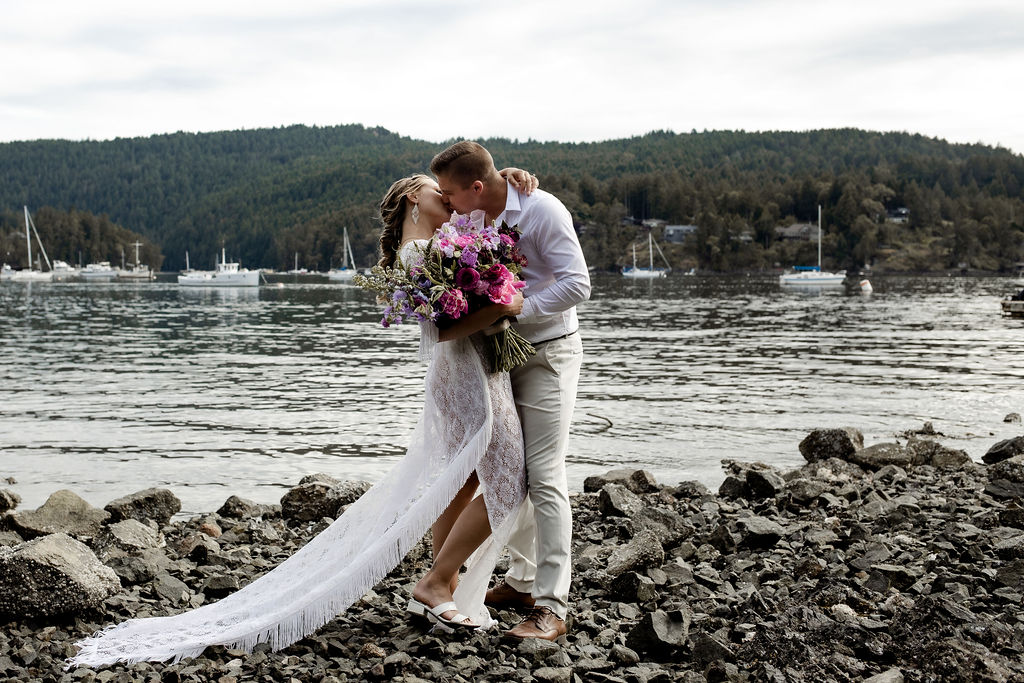 Newlyweds kiss along the ocean edge on Vancouver Island